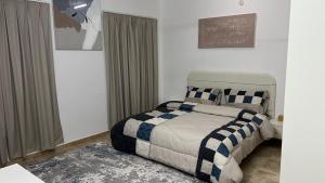 a bedroom with a bed with a blue and white blanket at المسارات الدولية in Mawāliḩ