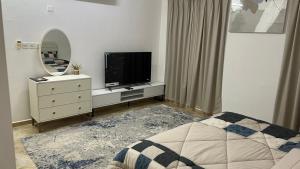 a bedroom with a television on a dresser with a mirror at المسارات الدولية in Mawāliḩ +4 photos