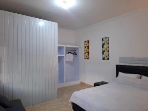 a bedroom with a white bed and a closet at Hillside guest house and restaurant in Gitgit