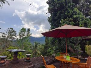 a table with a red umbrella on a patio at Hillside guest house and restaurant in Gitgit