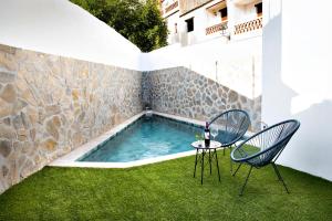 a pool with two chairs and a table in a yard at Oasis de Cañar in Cáñar