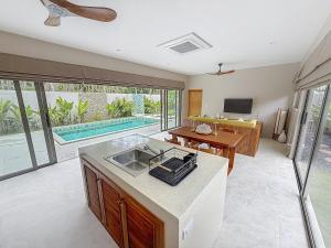 een keuken met een gootsteen en een woonkamer met een zwembad bij Villa Souimanga 2Bed Balinese style Garden & Pool in Mae Nam