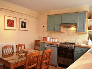 a kitchen with blue cabinets and a table and a table and chairs at Valentine Cottage in Keswick