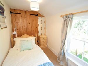 a bedroom with a bed with a wooden headboard and a window at Salters Cottage - E5045 in Wainfleet All Saints