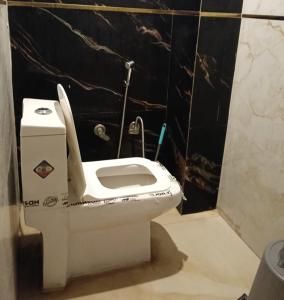 a white toilet in a bathroom with a black wall at Hotel Kaushalya in Ayodhya +7 photos