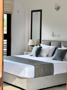 a bedroom with a large bed with white and gray pillows at Villa southern coast in Kamburugamuwa