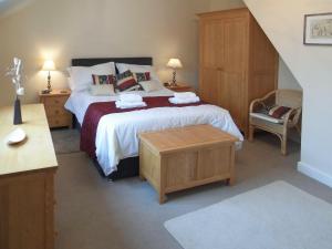 a bedroom with a large bed and a table at School Knott Cott in Windermere