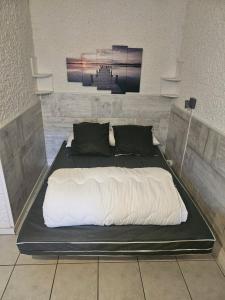 Elle comprend un grand lit avec des draps blancs et des oreillers noirs. dans l'établissement PALMA II, à Port-la-Nouvelle