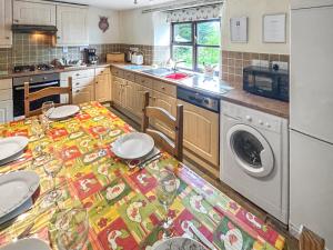 a kitchen with a table with a washing machine at Cider Cottage in Hawkchurch