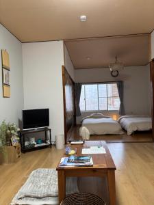 a living room with two beds and a table at ゲストハウス樹 in Shingū