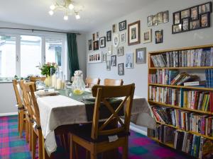 a dining room with a table and chairs and bookshelves at Tigh Raineach in Strathyre