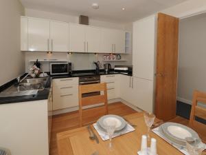 a kitchen with white cabinets and a wooden table at Tidal Bay in Westward Ho