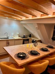 a kitchen with a wooden table with plates and wine glasses at Le Nid de Schatzi in Haguenau