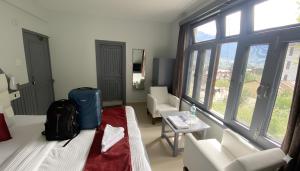 a room with a bed and a suitcase and a table at Hotel Sunrise Meadows Mountain in Manāli