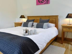 a bed with two mugs and a tea kettle on it at Sgubor Ucha in Trefriw +15 photos