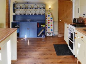 a kitchen with blue cabinets and wooden floors at Bat's Cottage in Tipton Saint John