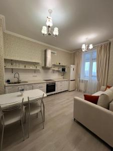 a kitchen and living room with a table and a couch at Квартира в центре города in Astana