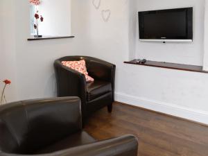 a living room with a chair and a flat screen tv at Craven House in West Burton