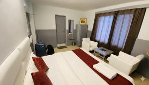 a bedroom with a large white bed and chairs at Hotel Sunrise Meadows Mountain in Manāli