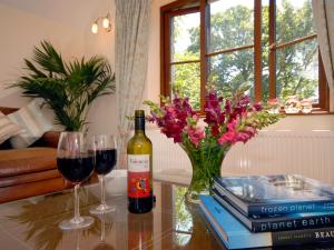 eine Flasche Wein und zwei Gläser auf einem Tisch in der Unterkunft The Hayloft in Walton West + 16 Fotos