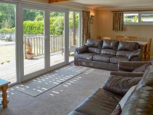 a living room with a leather couch and sliding glass doors at Watersedge - E1106 in Horning