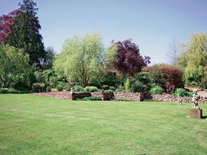 a garden with a stone wall and a grass field at Bridle Cottage in Hoarwithy +2 photos