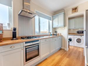 a kitchen with white cabinets and a stove top oven at Beach Haven - Uk42241 in Littlestone-on-Sea +19 photos