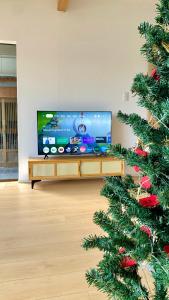 ein Wohnzimmer mit einem TV und einem Weihnachtsbaum in der Unterkunft Okayama Garden House Near Station Free Parking in Okayama + 35 Fotos