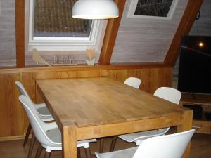 a dining room with a wooden table and white chairs at Norddachhaus in Damp