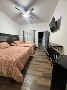 a bedroom with two beds and a ceiling fan at Hotel Cuatro Palmas in Puerto Peñasco