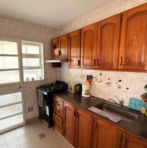 a kitchen with wooden cabinets and a sink and a stove at Departamento Impecable Luminoso! in Azul