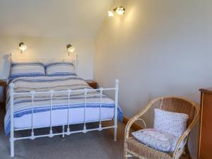 a bedroom with a bed and a chair at Gunluk Cottage in Brompton +9 photos