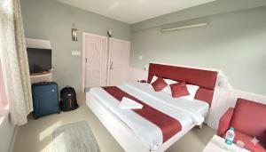 a bedroom with a large bed with a red headboard at Hotel Sunrise Meadows Mountain in Manāli +9 photos