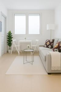 a white living room with a couch and a table at Apartamentos La Gringa Centro Gijon II Obra nueva con posibilidad de Parking in Gijón