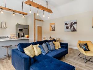 Una sala de estar con un sofá azul y una cocina. en Dip Tub Den - Uk35989, en Wansford