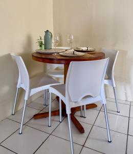 a dining room table with white chairs and wine glasses at Loft Central Orgânico in Passos