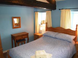 ein Schlafzimmer mit einem Bett, einem Tisch und einem Spiegel in der Unterkunft Blease Cottage in Threlkeld