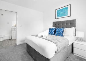 een witte slaapkamer met een groot bed met blauwe kussens bij Stylish 2 Bed Apartment - Smart TV - WiFi - Parking 27C in Sleightholme