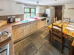 a kitchen with a table and a sink and a refrigerator at Cider Cottage in Hawkchurch