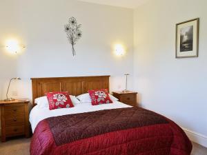a bedroom with a large bed with red pillows at Swallows Nest in Soulby +7 photos