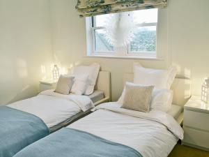 deux lits dans une chambre avec une fenêtre dans l'établissement Tower Cottage - Mvw, à Belsay 7 autres photos
