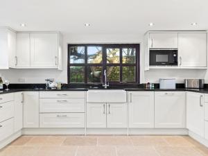 a white kitchen with white cabinets and a window at Morfa Ganol in Llangranog