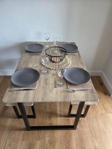 Una mesa de madera con platos y copas de vino encima. en Little Fairacre - Two double bedroom annexe, en Braunton