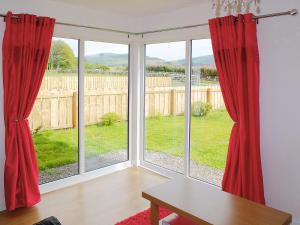 a room with a large window with red curtains at Myrtle Cottage - 28177 in Fairgirth