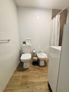 a white bathroom with a toilet and a sink at Studio 16 Neuquén in Neuquén