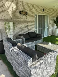 een patio met 2 rieten stoelen en een bank bij גארדן בוטיק צימר בכפר in Mishmar Hashiv‘ah +2 foto's