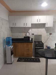 a kitchen with white cabinets and a table in it at 1 bedroom BNB Meru in Meru