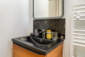 a bathroom with a black sink and a mirror at L'Escapade Médiévale Appartement neuf in Josselin