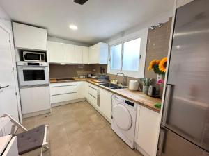 a kitchen with white cabinets and a sink and a dishwasher at Rooms Borrells in Barcelona