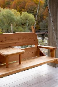 a wooden swing on a porch with trees in the background at Mizhhirya resort in Mizhhirya +14 photos